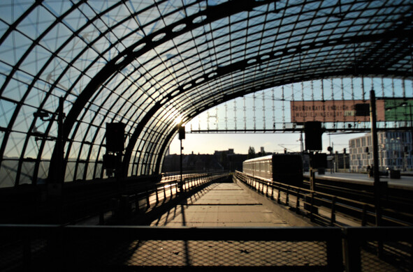 a view of looking east out of Berlin main station, with a train just leaving under the patterned glass roof of the station